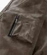 Campera bomber de poliuretano con acabado efecto cuero, cuello redondo, cierre frontal con cremallera, bolsillos delanteros y bolsillo utilitario en la manga. Presenta puños y ruedo elásticos, con forro interior en contraste.