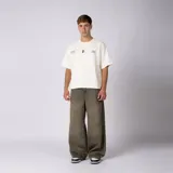 Remera boxy de color crudo con hombro caído y corte cuadrado a la cadera. En el frente presenta un diseño minimalista con texto y un pequeño logo central.