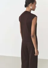 Camiseta color beige de tejido fluido con cuello asimétrico, diseño recto y detalles fruncidos.