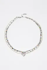Collar multicapa compuesto por una tira de perlas cultivadas, una cadena metálica con cuentas de colores y tubos plateados, y una tira adicional con un dije colgante en forma de corazón.