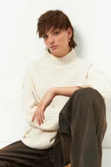 Polera gris de tejido tramado, cuello alto y mangas holgadas.