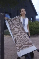 Chal de lana con diseño de patrón paisley y detalles de puntos, con terminación de pompones en los extremos.