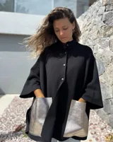 Saco tejido de punto en color negro, con corte holgado y mangas tres cuartos. Presenta bolsillos frontales amplios confeccionados en cuero metalizado color plateado y cierre frontal con botones.