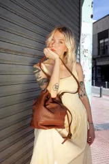 Cartera tipo botellero color marrón con efecto trenzado, tamaño mediano, cierre con frunce, correa ajustable con hebilla para usar al hombro o cruzada, doble bolsillo interior (uno con cierre).