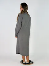 Vestido camisero midi de corte recto y holgado, con cierre frontal de botones, cuello camisero, mangas largas con puños abotonados y bolsillos frontales superiores con solapa.