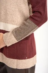 Cardigan abierto de punto con diseño de bloques de color en tonos beige, marrón y bordó. Presenta mangas largas, corte recto y bolsillos frontales aplicados.