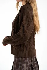 Cardigan de punto con diseño de trenzas, color marrón oscuro, con escote en V, cierre frontal de botones dorados y bolsillos delanteros.