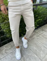 Pantalón slouchy de corte ancho y relajado, color beige, con diseño desgastado y roturas en las rodillas.