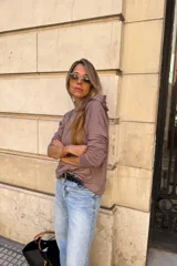 Canguro con capucha de manga larga, color marrón topo, de calce amplio y tejido suave. Presenta bolsillo canguro frontal y puños y ruedo ajustados.