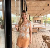 Chaleco de cuero tostado en el frente con apliques de grandes flores de crochet blancas, y espalda de tejido de punto de algodón. Presenta cuello redondo y diseño sin mangas.