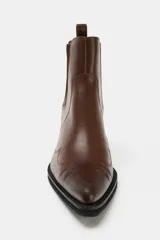 Botín cowboy de piel color marrón con detalles bordados en el cuerpo, elástico lateral, tirador trasero y tacón ancho en bloque con acabado en punta.