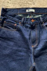 Pantalón de jean azul oscuro con corte baggy y calce relajado. Presenta cinco bolsillos clásicos y costuras reforzadas en tono contrastante.