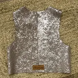 Chaleco de cuero con acabado metalizado plateado, diseño sin mangas, escote en V y corte recto.