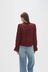 Blusa de viscosa color bordó con diseño bordado geométrico, cuello en V y mangas largas con terminación en volados.