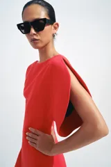 Vestido midi de cuello barco y manga corta abullonada, color rojo, con diseño asimétrico en el bajo en línea evasé y cierre trasero con cremallera oculta.