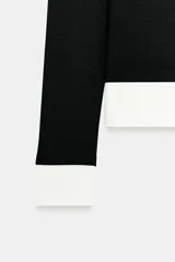 Camiseta de manga larga color gris melange, con cuello redondo y bajo recto. Presenta un detalle de tejido efecto doble a contraste en el cuello, puños y dobladillo inferior en color blanco.