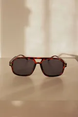 Lentes de sol con marco de policarbonato en patrón carey y cristales oscuros. Presentan un diseño de puente doble y detalle metálico en las bisagras. Cuentan con protección UV400 e incluyen estuche.