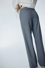 Pantalón sastrero gris de tiro alto, con pliegues marcados al frente y piernas anchas y rectas.