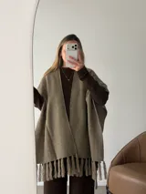 Ruana negra de tejido liviano con terminación de flecos en el ruedo y mangas amplias.