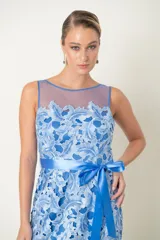Vestido largo de fiesta celeste con encaje floral, hombros descubiertos con tul y lazo azul en la cintura.