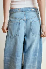 Jeans de tiro medio y diseño balloon, color azul denim con efecto lavado, cinco bolsillos, cierre frontal con cremallera y botón metálico, y bajos acabados en puño.