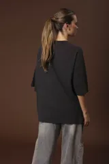 Remera negra de corte oversize con estampado abstracto en tonos rojos, grises y blancos.