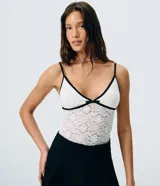 Body de encaje blanco con transparencia sutil, escote en V con ribete negro y un pequeño lazo decorativo al centro, breteles finos y diseño ajustado al cuerpo de la marca Blue Steel.