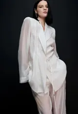 Blazer de sastrería color beige con textura satinada, solapas de muesca, bolsillos con solapa y detalle fruncido con cordones ajustables en la cintura.