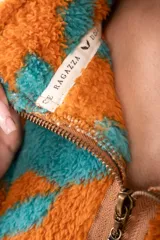 Campera corta de polar color beige con estampado de estrellas negras, cuello alto y cierre frontal.