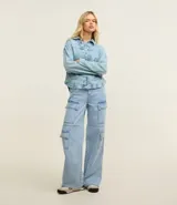 Pantalón de jeans celeste, corte wide leg, con bolsillos cargo laterales, cintura alta con trabillas y cierre con botón y cremallera.