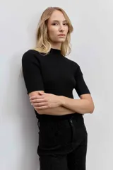 Blusa de punto acanalado en color negro, con cuello alto y mangas cortas ajustadas.