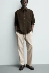 Pantalón de corte relajado confeccionado en una mezcla de algodón y lino. Presenta cintura elástica con cordón ajustable, bolsillos laterales y bolsillos traseros de vivo.