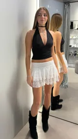 Minifalda short blanca de encaje con volados en capas y diseño de tiro bajo.