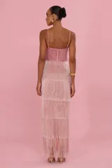 Vestido largo Patbo de tirantes, confeccionado en tono rosa, con diseño de múltiples capas de flecos y aplicación bordada tridimensional en el pecho con detalles dorados.