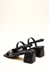 Sandalia de cuero vacuno color negro con textura de cocodrilo, taco cuadrado de 4 cm, punta cuadrada y dos tiras finas, una en el empeine y otra con hebilla en el tobillo.