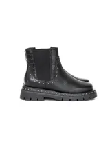Bota de caña corta de cuero negro, con elásticos laterales y suela track gruesa con tachas metálicas alrededor delribete. Cuenta con detalles de textura croco en los laterales y tachas decorativas.