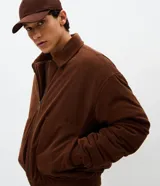 Campera bomber de pana color marrón, con cuello polo, cierre frontal con cremallera y puños y bajo elásticos.