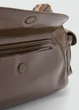 Bolso de hombro estilo hobo en color marrón oscuro con acabado brillante. Presenta un diseño estructurado con múltiples bolsillos exteriores con cierre frontal y laterales, herrajes metálicos dorados y asa fija.