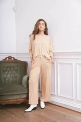 Remerón de tela acanalada color beige, con corte holgado, mangas tres cuartos y aberturas laterales en el ruedo.