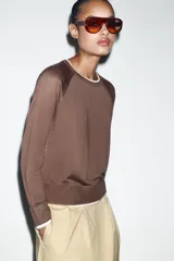 Jersey de punto efecto doble, color azul marino con detalles en blanco en el cuello, puños y ruedo. Presenta cuello redondo y manga larga con diseño de hombros raglán.
