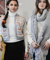 Chal oversized tejido a mano en técnica crochet con lana merino, color gris, con diseño texturizado de granny square y largos flecos en los extremos.