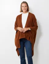 Ruana de tejido soft, color marrón óxido, de corte amplio y sin cierres, con cuello redondo.