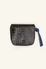 Billetera compacta de cuero negro con textura de reptil, cierre perimetral y tirador decorativo con nudo en color azul.