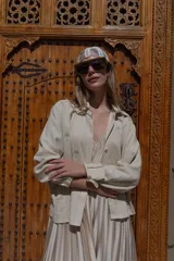 Camisa de lino color beige con bordados de palmeras en hilo plateado. Tiene cuello camisero, mangas largas con puños y cierre frontal con botones.