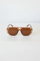 Lentes de sol con armazón de policarbonato negro y cristales tonalidad ámbar, con diseño de puente doble estilo aviador.