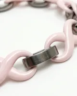 Pulsera de eslabones de acero inoxidable alternados con dijes de cerámica en forma de infinito color rosado.