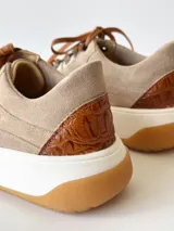 Championes de cuero color visón con cordones marrones, suela blanca y base color caramelo.