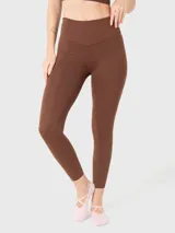 Calza deportiva de tiro alto y largo al tobillo, confeccionada en tejido elástico color marrón chocolate. Presenta un diseño liso sin bolsillos con costuras reforzadas en la cintura.