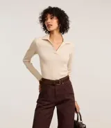 Blusa de manga larga confeccionada en tejido rib de algodón con elastano. Presenta un diseño ajustado al cuerpo con cuello polo y escote en V.