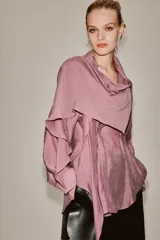Camisa de manga larga confeccionada en mezcla de lyocell, con cuello fluido tipo pañuelo integrado, cierre frontal con botones ocultos por solapa y bajo redondeado asimétrico.